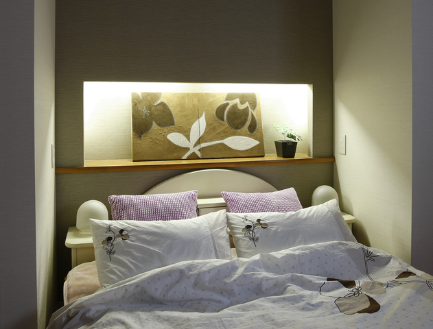 主寝室の壁はクロスの色を変えた棚を設けました。間接照明が優しい雰囲気の枕元に...