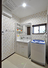 スペースを広げ収納付きの洗面化粧台（TOTO／サクア）と洗濯機を設置。入口は引き...