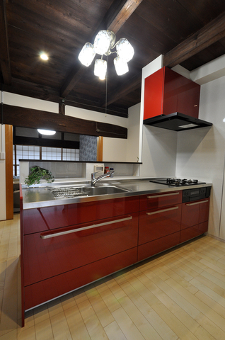 キッチンは梁や天井の焦げ茶色と相性の良いワインレッド（クリナップ/ステディア...
