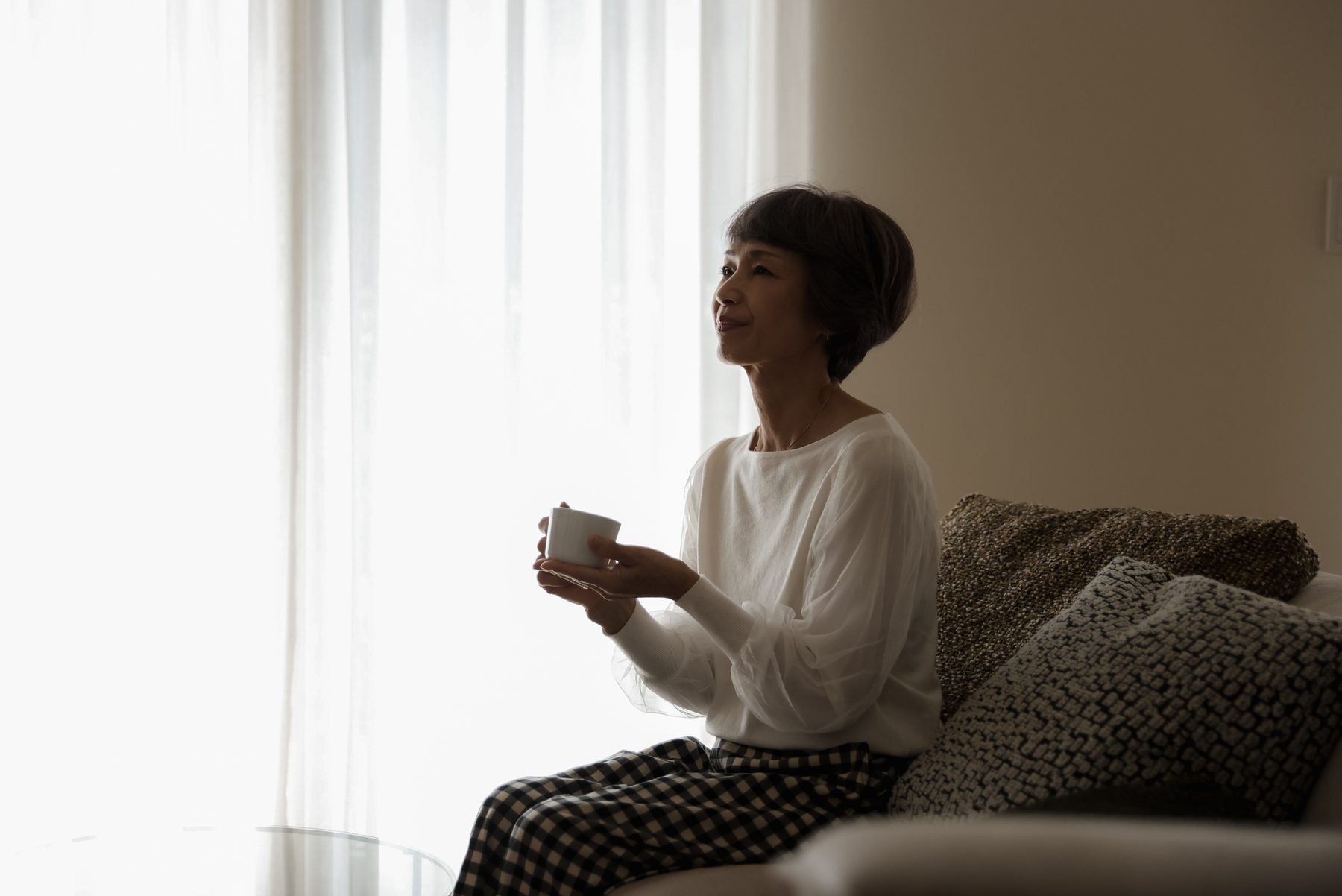 窓辺でマグカップを手に、ひと息ついている様子